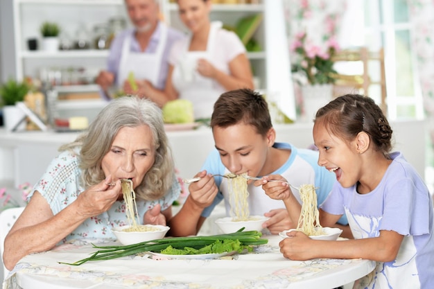 Portret babci i wnuków jedzących razem śniadanie w kuchni