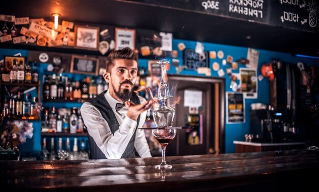 Portret barmana, wlewając świeży napój alkoholowy do szklanek w nocnym klubie