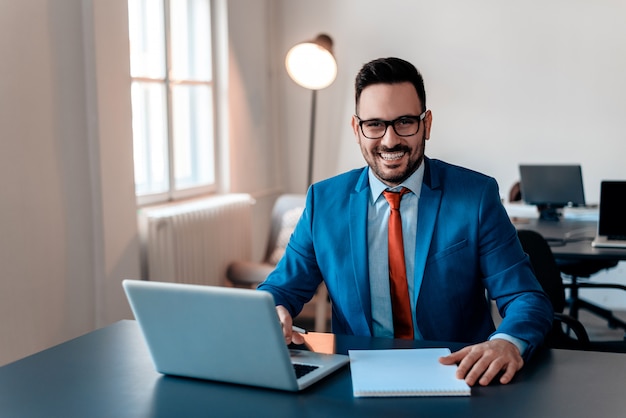 Portret biznesmen przy biurowym biurkiem używać laptop.