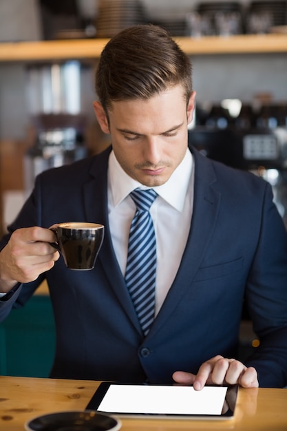 Portret biznesmen używa cyfrową pastylkę w kawiarni