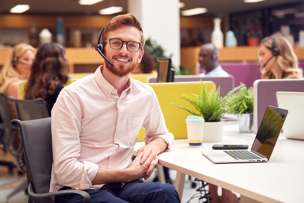 Portret biznesmena noszącego zestaw słuchawkowy, rozmawiającego z rozmówcą w centrum obsługi klienta