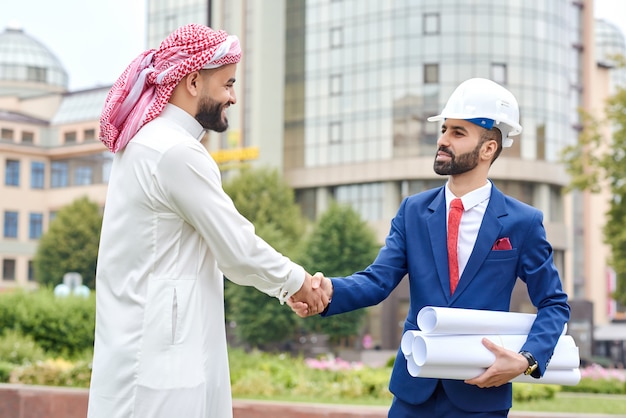 Portret Biznesmena Z Arabii Saudyjskiej, ściskając Ręce Z Architektem Na Zewnątrz W Rozwijającym Się Mieście