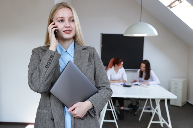 Portret bizneswoman rozmawiającej przez telefon na tle pracującego biura