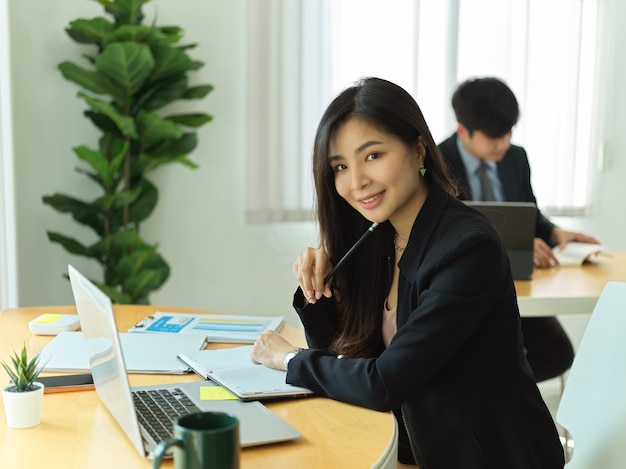 Portret Bizneswoman Uśmiecha Się Podczas Pracy Z Laptopem I Papierkową Robotą W Biurze