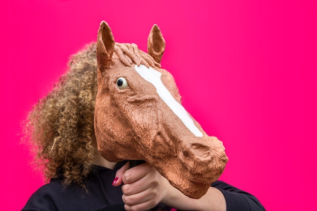 Zdjęcie portret blondynki dziewczyny kędzierzawa mienie zabawka końska głowa na jaskrawym menchiach.