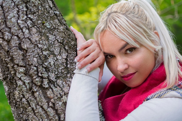 Portret blondynki kobieta opiera na drzewnym bagażniku park