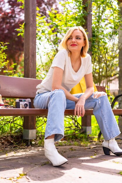 Portret blondynki turystki siedzącej na ławce w parku na wakacjach