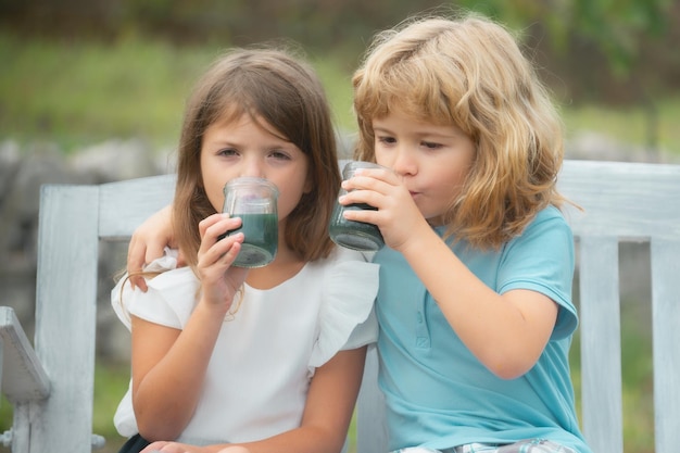 Portret brata i siostry piją smoothie dla dzieci letni koktajl w letnim parku na zewnątrz Mały chłopiec i dziewczynka dzieci cieszą się latem na podwórku Najlepsi przyjaciele dwójki dzieci