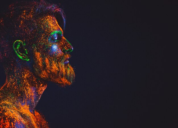 Portret brodatego mężczyzny. Człowiek jest pomalowany proszkiem ultrafioletowym.