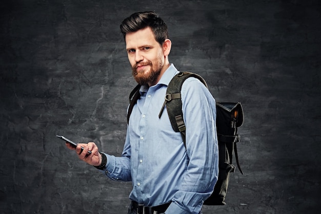 Portret Brodatego Mężczyzny Podróżnika Miejskiego Z Plecakiem Na Plecach, Patrzącego Na Tor Gps Za Pomocą Smartfona.