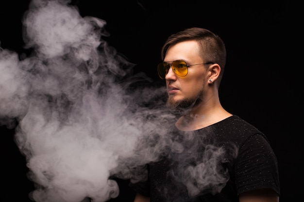 Portret brodaty mężczyzna na czarnym zakończeniu. Vape człowiek.