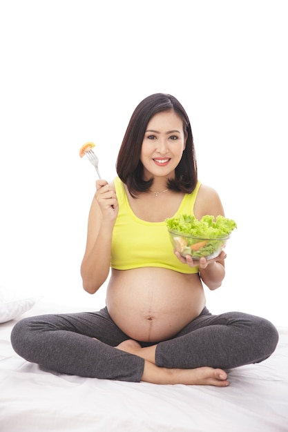 Portret całego ciała kobiety w ciąży, trzymając miskę zdrowej sałatki