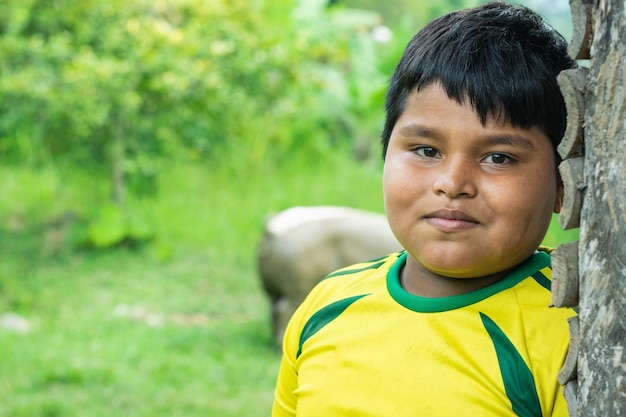 portret chłopca indian latynoamerykańskich, opierając twarz na ścianie wykonanej z drewnianych puszek.