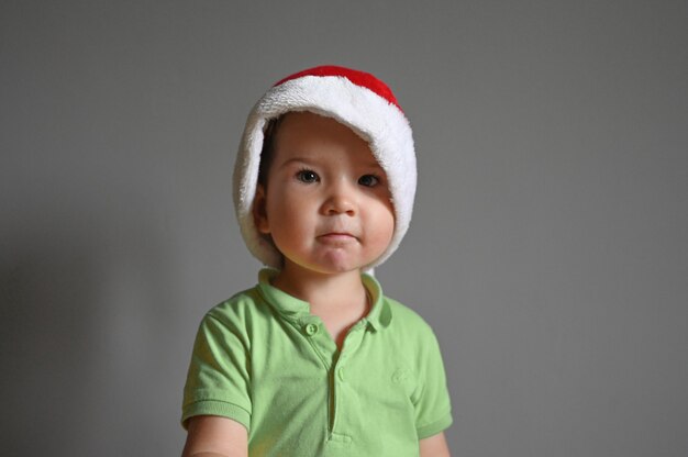 Portret Chłopca Kaukaski Maluch W Santa Hat. Na Szarym Tle, Miejsca Na Tekst. Zdjęcie Wysokiej Jakości