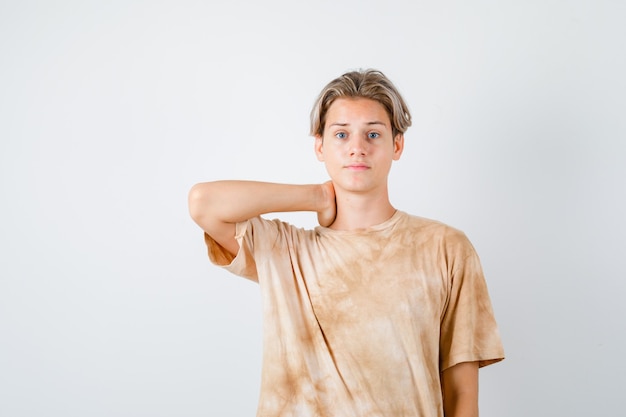 Zdjęcie portret chłopca nastolatka trzymającego rękę na szyi w koszulce i patrzącego na zmartwiony widok z przodu