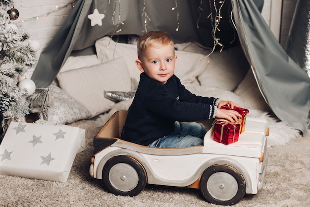 Zdjęcie portret chłopca pokazuje świąteczne pudełka z prezentami