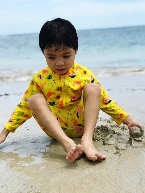 Zdjęcie portret chłopca siedzącego na plaży