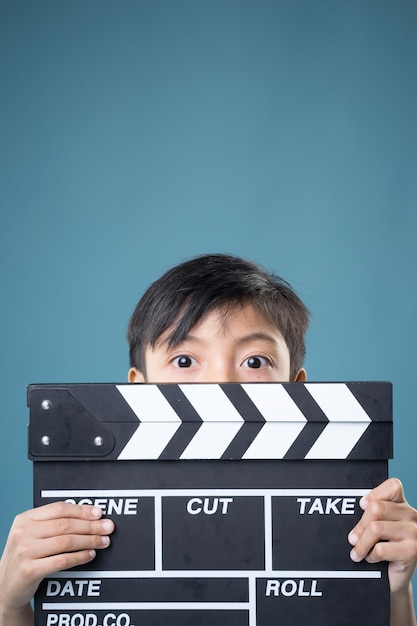 Zdjęcie portret chłopca trzymającego łupek filmowy stojący na niebieskim tle
