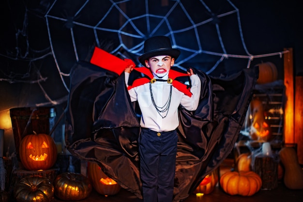 Portret chłopca ubranego w kostium wampira i kapelusz na tło grunge. Impreza halloween'owa.