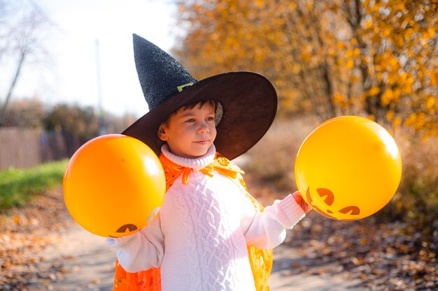 Portret chłopca w Halloween ubrania z balonami dyni na ulicy. Tradycyjne święto. 31 października.