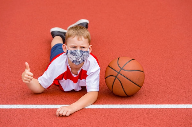 Zdjęcie portret chłopca w masce leżącego na boisku sportowym