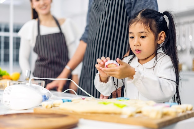 Portret ciesz się szczęśliwą miłością azjatyckiego rodzinnego ojca i matki z małą azjatycką dziewczyną córką, dzieci bawią się i bawią, gotując jedzenie wraz z pieczeniem ciasteczek i składników ciasta w kuchni