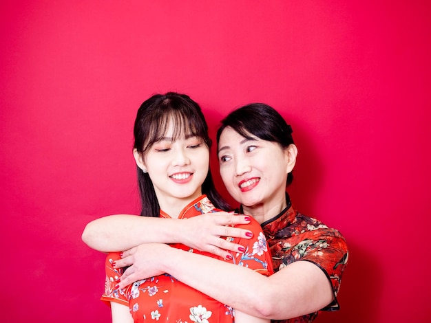 Portret Córki I Matki Noszących Tradycyjne Qipao Qipao I Uśmiechnięte Przytulanie Na Czerwonym Tle