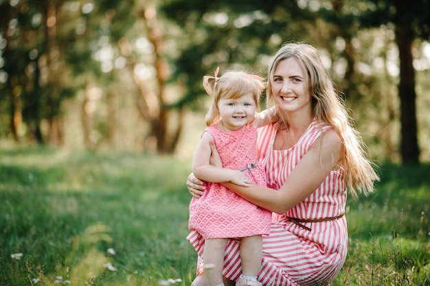 Zdjęcie portret córki przytulająca matkę na łonie natury na letnie wakacje mama i dziewczyna bawiące się w parku o zachodzie słońca koncepcja przyjaznej rodziny zbliżenie