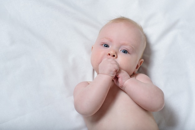 Portret Cute Blond Dziecko Z Palcami W Ustach. Biała Kartka. Widok Z Góry