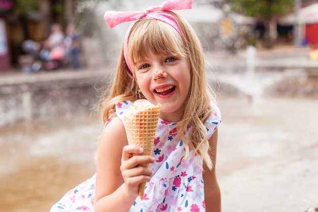 Portret cute blond dziewczynka z lodami na spacer w parku.