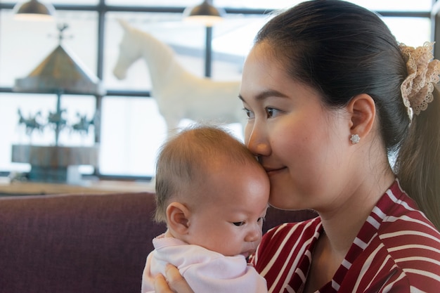 Portret cute noworodka w ręce matki. Piękna mama trzyma ślicznego syna śmiać się. Zbliżenie w połowie kobieta z jej małym chłopcem. Nowa koncepcja rodziny i miłości.