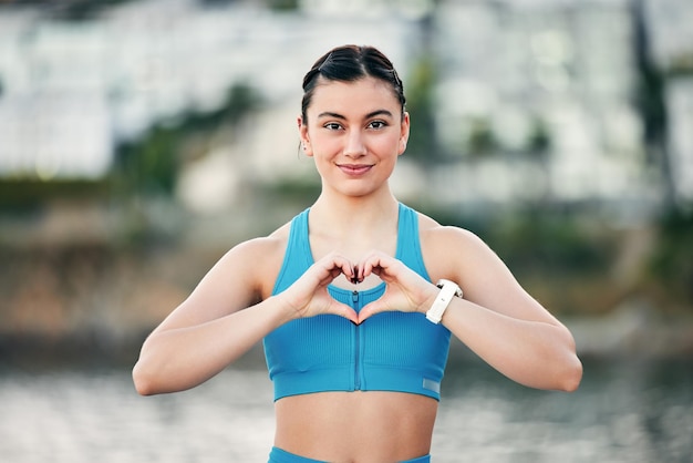 Portret ćwiczący i kobieta z ręką serca dla dobrego samopoczucia, zdrowia i szczęścia podczas odpoczynku w biegu Biegacz fitness i młodzież z miłością podpisują przerwę w treningu, aby dbać o siebie i uśmiechać się w naturze