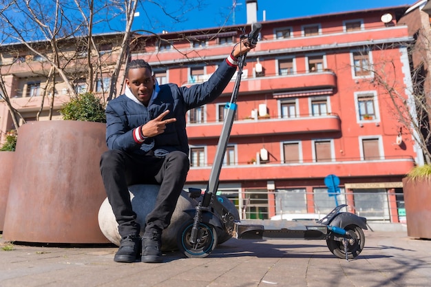 Portret czarnego etnicznego mężczyzny jeżdżącego na deskorolce na elektrycznej deskorolce w mieście nowa mobilność w parku