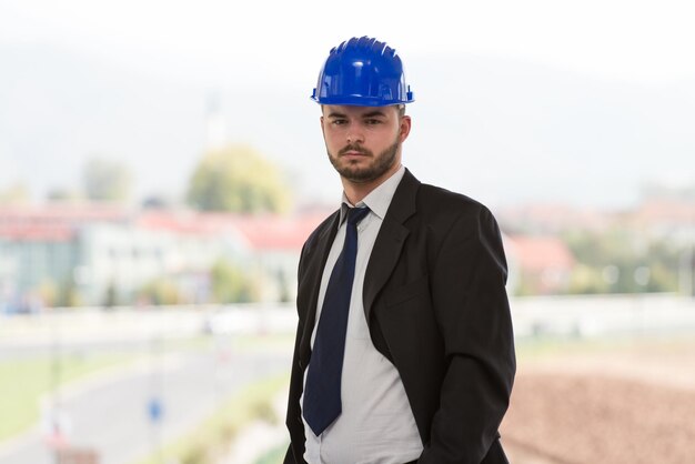 Portret człowieka biznesu z niebieskim hełmem na budowie
