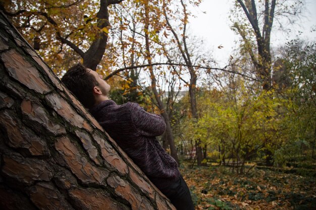 Zdjęcie portret człowieka siedzącego na pniu drzewa w lesie