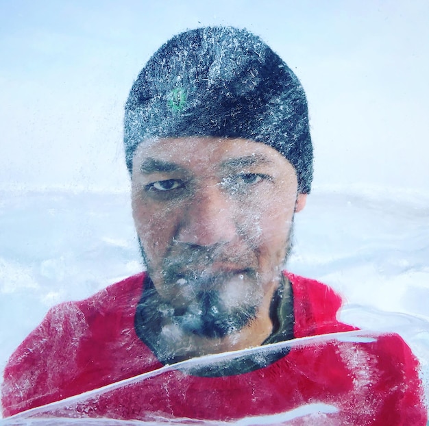 Portret człowieka w śniegu widziany przez szklane okno