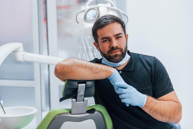 Zdjęcie portret dentysty w rękawiczkach, który stoi w pomieszczeniu w klinice.