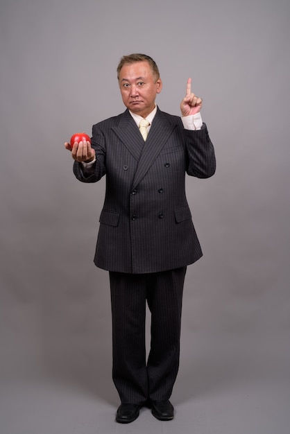 Portret dojrzałego biznesmena azjatyckich przeciw szarej ścianie