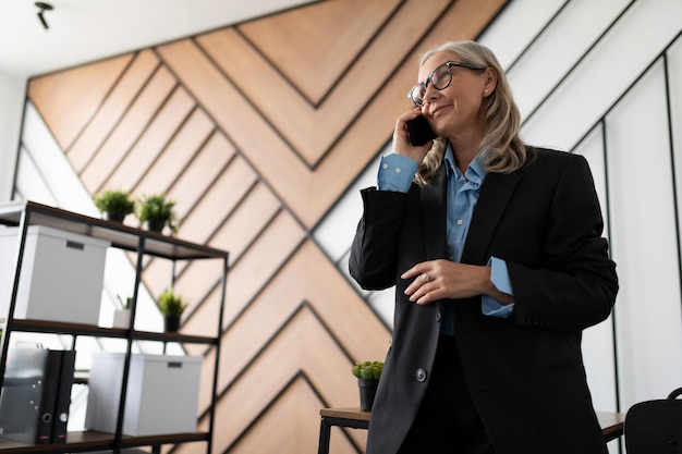 Portret dojrzałej, dorosłej kobiety, szefowej, rozmawiającej przez telefon w biurze