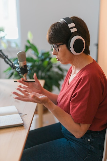 Portret dojrzałej kobiety w słuchawkach i rozmawiającej w internetowej stacji radiowej podcast i koncepcja transmisji