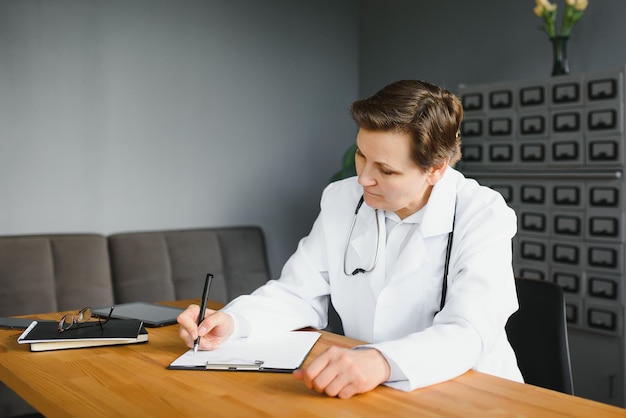 Portret dojrzałej lekarki w białym fartuchu w miejscu pracy