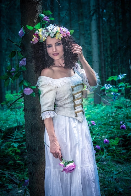 Portret dorosłej kobiety w białej sukience stojącej w lesie