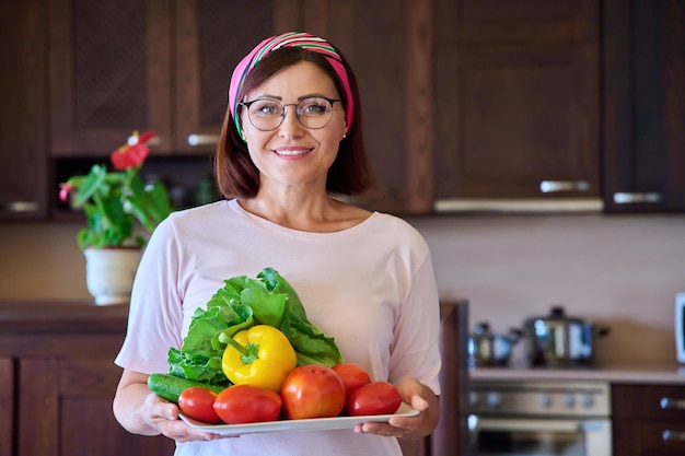 Portret dorosłej kobiety z talerzem warzyw w kuchni