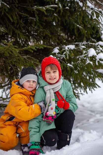 Portret dwóch dziewczyn w pobliżu pokrytego śniegiem drzewa na spacerze zimą