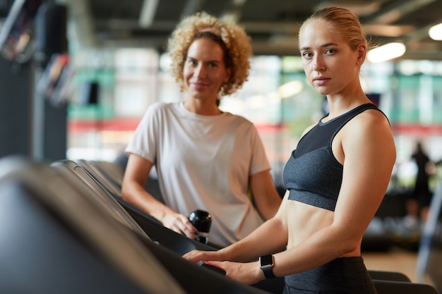 Portret dwóch kobiet sportowy patrząc na kamery podczas treningu na siłowni