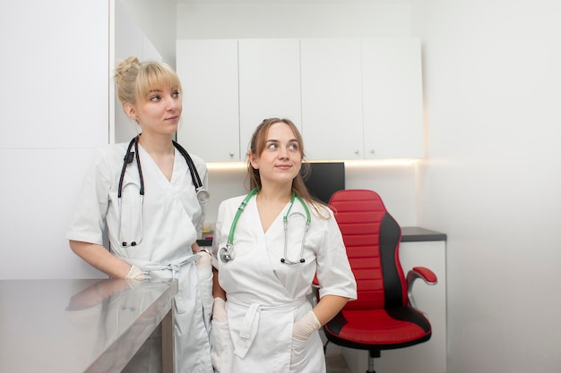 Portret dwóch lekarek w fartuchach medycznych w klinice na tle miejsca pracy