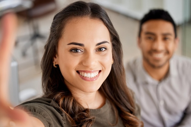 Portret dwóch młodych biznesmenów robiących selfie w nowoczesnym biurze