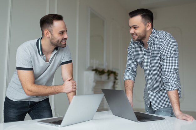 Portret dwóch pewny siebie biznesmen pracuje na laptopie. Jeden mężczyzna rozmawia na smartfonie, gdy inny facet wskazuje palcem na ekranie.