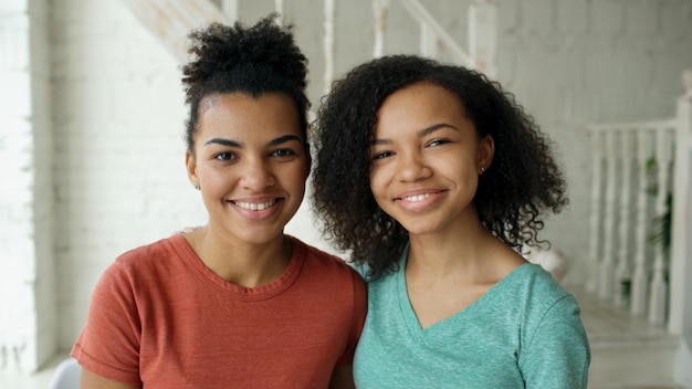 Portret dwóch pięknych afroamerykańskich dziewczyn śmiejących się i patrzących w kamerę w domu