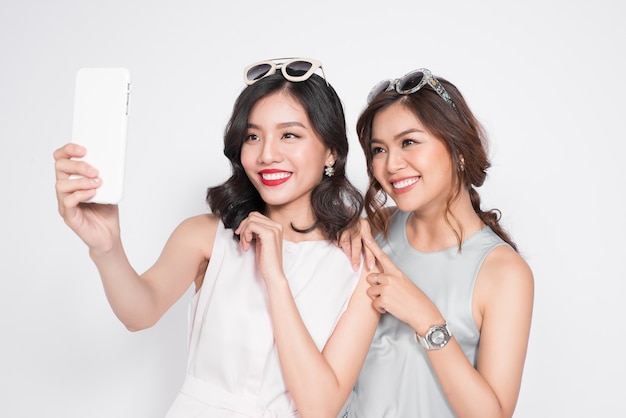 Portret dwóch pięknych azjatyckich modnych kobiet biorących selfie